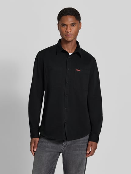 Männermodel trägt Straight Fit Hemdjacke aus Baumwolle Modell 'Egrin' von HUGO in Schwarz, glatte Struktur, Herren Hemdjacke, Ganzkörperansicht von vorne.