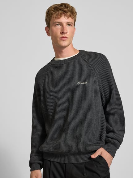 Männermodel trägt Relaxed Fit Strickpullover aus reiner Baumwolle Modell 'Campus' von PROHIBITED, dunkle Farbe, gerippte Textur, Nahaufnahme Oberkörper, Herren Strickpullover, KI-modifiziertes Bild.