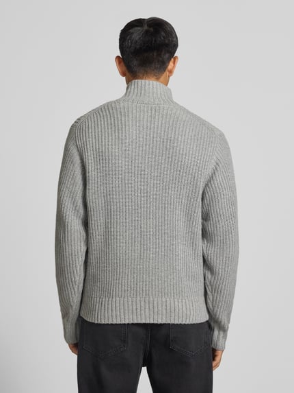 Männermodel trägt Troyer mit Brustleistentasche Modell 'DETROIT' von Carhartt Work In Progress in Grau, Strukturstrick, Ganzkörperansicht Rückansicht. Material-Mix mit Woll-Anteil, Regular Fit, Troyer-Kragen, Label-Patch, Rückenlänge 68 cm, Ärmellänge 56 cm.