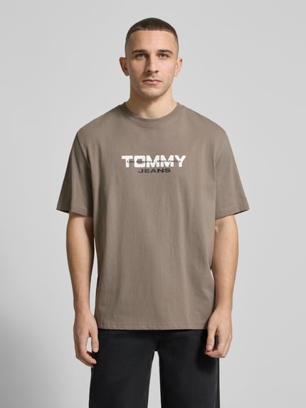 Mannelijk model draagt Regular Fit T-Shirt aus reiner Baumwolle van Tommy Jeans, effen, label-schrift, ronde hals, korte mouwen, katoen webstof, Ganzkörperansicht von vorne.