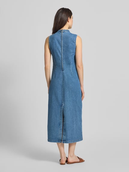 Frauenmodel trägt Jeanskleid mit Gehschlitz Modell 'WINONA' von Vila aus blauem Baumwoll-Mix mit Stretch-Anteil, Taillierter Schnitt, Rückseitiger Reißverschluss und Rückseitiger Gehschlitz, Midikleid mit kurzem Stehkragen, Rückenlänge bei Größe S 129 cm, Brustweite bei Größe S 40 cm, Ganzkörperansicht Rückansicht.