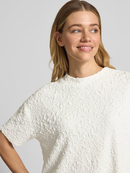 Vrouwenmodel draagt Relaxed Fit T-Shirt uit viscosemix model 'Keena' van Someday, structuurpatroon, ronde hals, detailopname bovenlichaam.