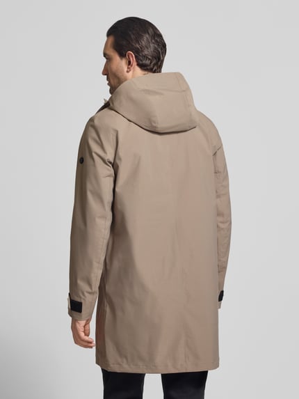 Männermodel trägt Parka mit mouwsluitingen Model 'GEORGE' van Didriksons in beige, regular fit, capuchon, ruglengte 94 cm, schouderbreedte 45 cm, borstwijdte 55 cm, mouwlengte 67 cm, ganzlichaamsaanzicht achteraan.