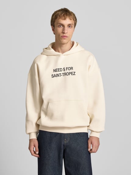 Mannenmodel draagt Oversized Hoodie aus Baumwoll-Mix Modell 'LEROY' van Only & Sons, unikle kleur, statementprint, sweatmateriaal, kangoeroezak, lange mouw, geribde boorden, vooraanzicht bovenlichaam.