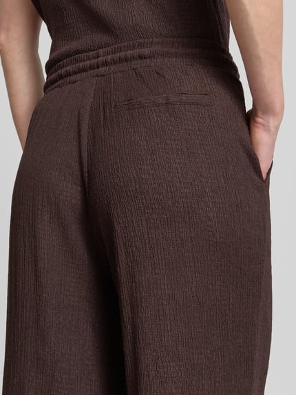 Frauenmodel trägt Wide Fit Stoffhose mit Strukturmuster Modell 'Mileni' von OPUS im Elastischer-Material-Mix, Detailaufnahme Rückenansicht.