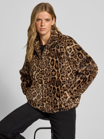 Frauenmodel trägt Jacke mit Stehkragen und Leomuster von REVIEW, Kunstfell, braune und schwarze Flecken, Reißverschluss, Nahaufnahme Oberkörper.