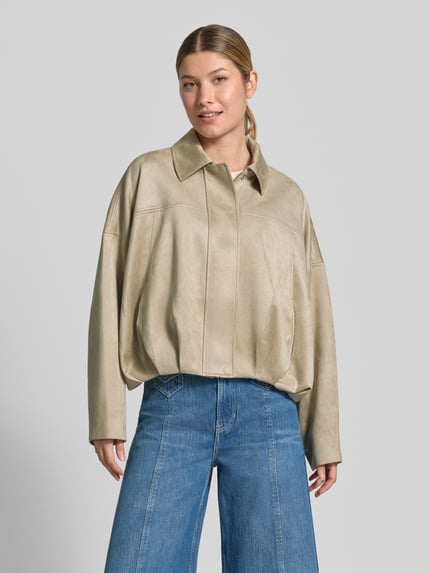 Frauenmodel trägt Relaxed Fit Blouson in Leder-Optik von COMMA in Beige mit Umlegekragen und Drapierungen, jeansblaue Hose, Ganzkörperansicht von vorne. Rückenlänge in S 52 cm, Brustweite 82 cm, Ärmellänge 45 cm.
