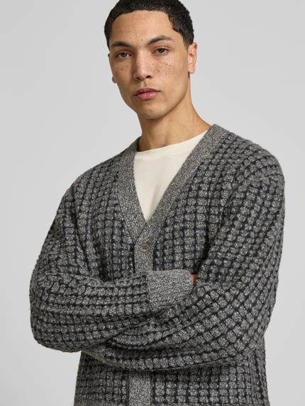 Männermodel trägt Strickjacke mit Bouclé-Strukturoptik von Officine Générale in grauer Melange-Strickoptik, Nahaufnahme Oberkörper.