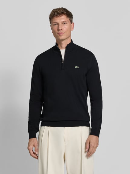 Männermodel trägt pullover met logopatch troyer van LACOSTE in look: effen met structuur, applicatie: logopatch, ritssluiting, schipperskraag, hooggesloten hals, mouwen: lang, mouwboord: geribd, rompzoom: geribd, materiaalverwerking: fijngebreid, geheelvooraanzicht.