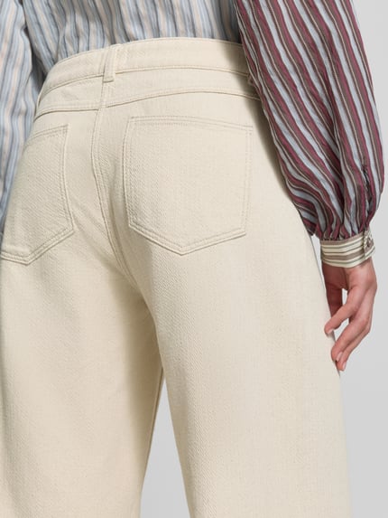 Frauenmodel trägt Wide Fit Jeans mit Strukturmuster von Jake*s Casual aus Reine Baumwolle, Gesäßtaschen, cremefarbene Textur, Detailaufnahme Rückansicht.