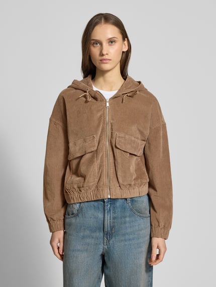 Frauenmodel trägt Oversized Bomberjacke aus Baumwoll-Mix Modell 'KENZIE' von ONLY in Cord, Optik: unifarben, aufgesetzte Vordertaschen, Reißverschluss, Kapuze mit Tunnelzug, Passform: Oversized, Materialverarbeitung: Baumwoll-Mix, ganzkörperansicht von vorne.