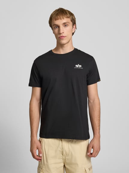 Männermodel trägt T-Shirt mit Logo und Rundhalsausschnitt von Alpha Industries, Herren T-Shirt aus Reine Baumwolle, Regular-Fit, Ganzkörperansicht von vorne. Rückenlänge bei Größe M: 67 cm.