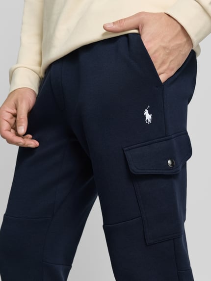 Männermodel trägt Sweatpants mit elastischem Bund von Polo Ralph Lauren aus Baumwoll-Elasthan-Mix, Label-Detail, Nahaufnahme Oberschenkel.