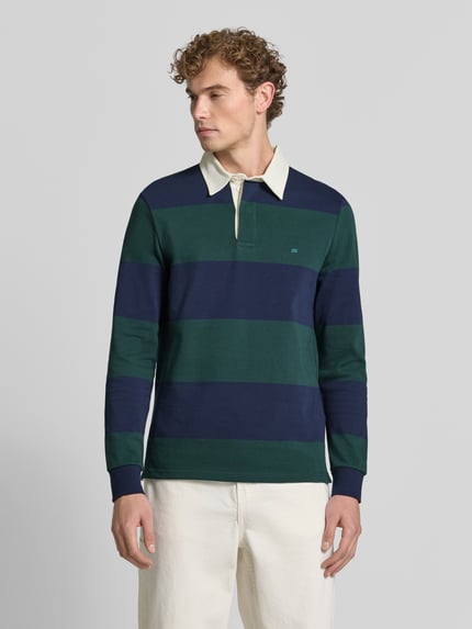 Männermodel trägt Poloshirt aus reiner Baumwolle von Christian Berg Men, breite grün-blaue Streifen, lockere Passform, Ganzkörperansicht von vorne.