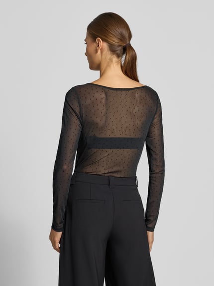 Frauenmodel trägt Slim Fit Longsleeve mit Punktemuster Modell 'OKTOBER' von COMMA in Schwarz mit eingefassten Abschlüssen, Rückenlänge 55 cm, Ganzkörperansicht Rückansicht.