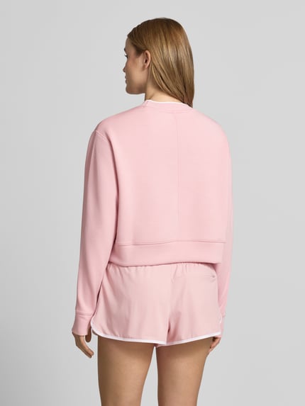 Frauenmodel trägt Cropped Sweatshirt Modell 'tasmin' von VARLEY in Rosa mit Modal-Mix, Stretch-Anteil, Rundhalsausschnitt, Ganzkörperansicht Rückansicht.