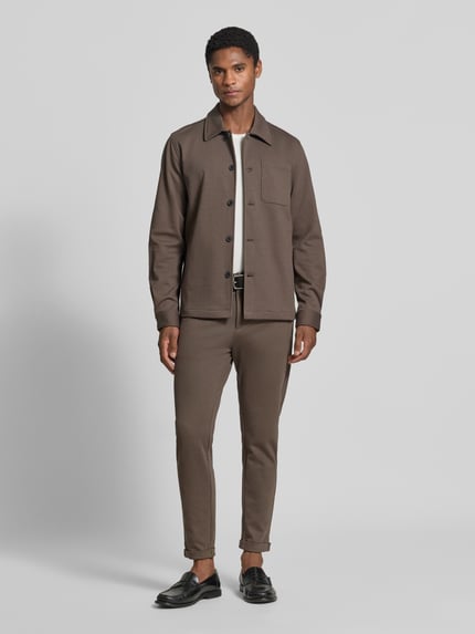Männermodel trägt Slim Fit Hemdjacke mit Viskose-Anteil von Lindbergh in Braun, elastisches Material, Umlegekragen, Ganzkörperansicht von vorne.