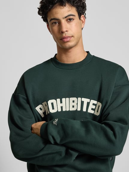 Männermodel trägt Oversized Sweatshirt mit Label-Detail von PROHIBITED, dunkles Grün, Baumwoll-Mix, Rundhalsausschnitt, Nahaufnahme Oberkörper.