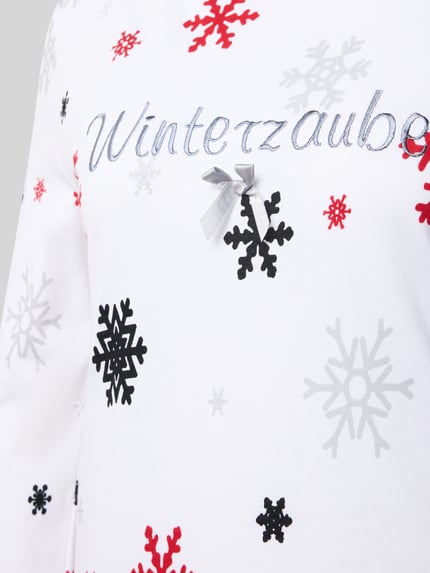 Vrouwenmodel draagt Nachthemd uit puur katoen Model 'Winterzauber' van LOUIS & LOUISA, getailleerde pasvorm, geborduurd motief, ronde hals, lang met sneeuwvlokkenprint, detailopname bovenlichaam.