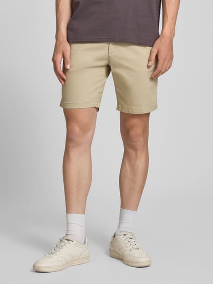 Männermodel trägt gerade, beigefarbene Straight Fit Shorts mit abnehmbarem Gürtel Modell 'Adam' von Jack & Jones, elastischer Baumwoll-Mix, Eingriff- und Gesäßtaschen, Knopf- und Reißverschluss, Ganzkörperansicht von vorne.