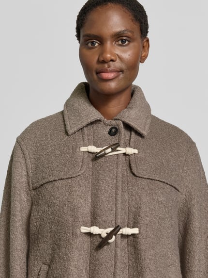 Frauenmodel trägt Relaxed Fit Dufflecoat aus Woll-Mix von Jake*s Casual in Taupe mit grober Textur und weißen Knebelverschlüssen, Nahaufnahme Oberkörper.