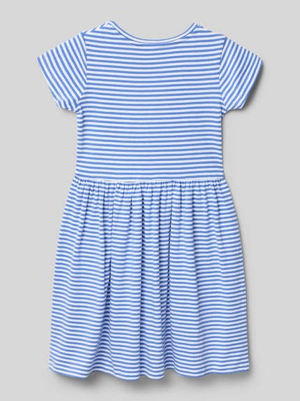 Mädchen trägt Regular Fit Shirtkleid mit Ziersteinbesatz von DANAMADE, krój regular fit, nakładane kieszenie, okrągły dekolt, z krótkim rękawem, taliowany krój, wyhaftowany motyw, długość tyłu w rozmiarze 116: 62 cm, niebiesko-białe paski, tekstura miękka, całość w paski, Ganzkörperansicht Rückansicht.