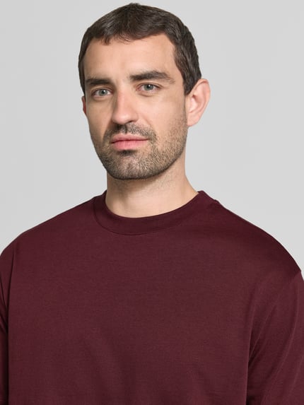 Männermodel trägt Regular Fit T-Shirt mit Rundhalsausschnitt von MCNEAL in Bordeaux, reine Baumwolle, Nahaufnahme Oberkörper.