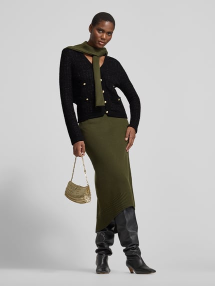 Frauenmodel trägt Cardigan mit goldfarbenen Zierknöpfen von Anine Bing in Strickoptik mit Struktur, Schwarz und Gold, Ganzkörperansicht von vorne.