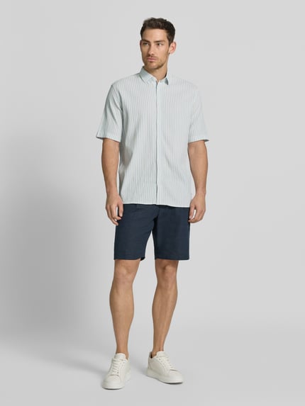 Männermodel trägt Comfort Fit Freizeithemd aus Lyocell-Baumwoll-Mix von Tom Tailor in Unifarbe mit Kentkragen, Ganzkörperansicht von vorne.