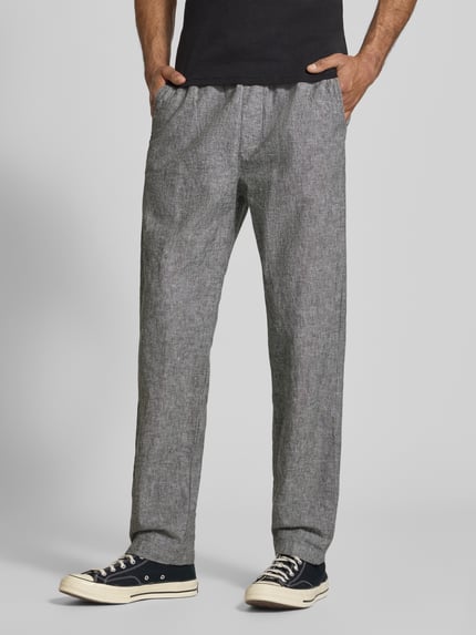 Männermodel trägt Regular Fit Weite HOSE aus Leinen-Baumwoll-Mix von Tommy Jeans in Melange-Optik, seitliche Eingrifftaschen, Ganzkörperansicht von vorne.
