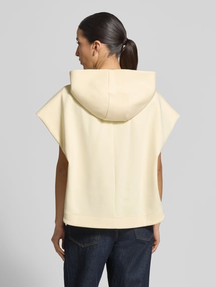 Vrouwenmodel draagt Loose Fit Sweatjacke aus Baumwoll-Mix Modell 'GATTINI' van MAX&Co., effen lichtgeel, zonder mouwen, sweatstof, rugaanzicht, context: dames sweatjack met capuchon, kangoeroezak, zijstretchelementen, labelopdruk, katoenmengsel, ritssluiting.