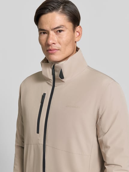 Mannenmodel draagt Regular Fit Jacke met Logoprint van Lindbergh in beige, elastische materiaalmix, Nahaufnahme Oberkörper. Ruglengte maat M 74 cm, schouderbreedte 46 cm, borstwijdte 42 cm, mouwlengte 62 cm.
