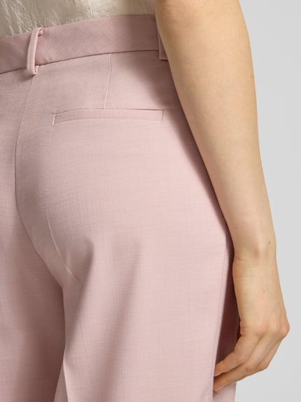 Frauenmodel trägt Hose aus Viskose-Mix mit Bügelfalten von More & More in Rosa, strukturierte Oberfläche, Nahaufnahme Rückansicht.