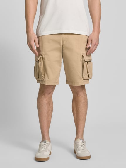 Männermodel trägt Shorts mit Cargotaschen Modell 'NEW 24' von GAP aus Baumwoll-Elasthan-Mix, Regular-Fit, beige, Ganzkörperansicht von vorne.