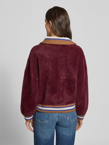 Frauenmodel trägt Strickjacke mit Kontrastkragen Modell 'KAMORE' von Essentiel Antwerp, mehrfarbig, gerippte Abschlüsse, Ganzkörperansicht Rückansicht.