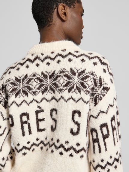 Frauenmodel trägt Pullover mit Ballonärmeln von VERO MODA in Jacquard-Strickoptik mit geometrischem Allover-Muster, Rückansicht.