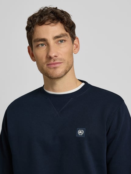 Männermodel trägt Sweatshirt mit Rundhalsausschnitt und Label-Patch von Lerros in Dunkelblau, Baumwoll-Mix, Nahaufnahme Oberkörper.