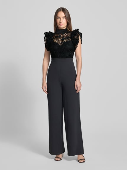Vrouwenmodel draagt Regular Fit Jumpsuit met florale kanten details van Lipsy, zwart met semitransparante top, Ganzkörperansicht von vorne.