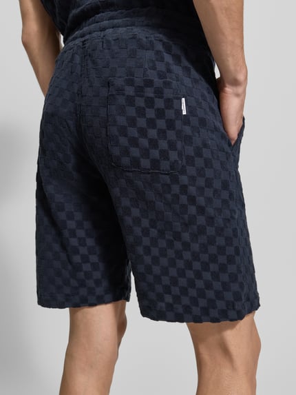 Männermodel trägt Regular Fit Shorts mit Label-Patch von Lindbergh aus dunkelblauem Baumwoll-Mix mit Eingrifftaschen und Gesäßtasche, Ganzkörperansicht Rückansicht.