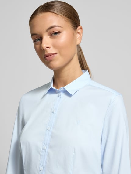 Frauenmodel trägt Hemdbluse aus Baumwoll-Mix von MARC O'POLO, taillierter Schnitt, Umlegekragen, Knopfleiste, Logo-Stickerei, Nahaufnahme Oberkörper.