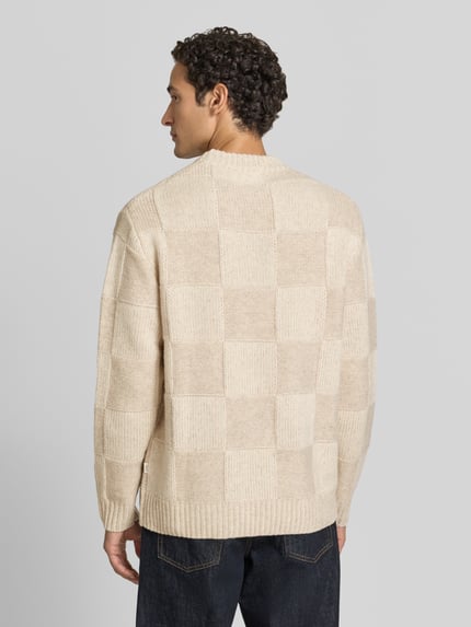 Męski model nosi sweter z dzianiny z okrągłym dekoltem od Les Deux z bawełny, prosty krój, prążkowane wykończenia, długość tyłu 72 cm, długość rękawów 66 cm, widok całej sylwetki z tyłu.