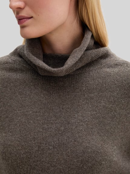 Frauenmodel trägt Rollkragenpullover mit überschnittenen Schultern von MARC O’POLO in unifarbener Strickoptik, Nahaufnahme Oberkörper.