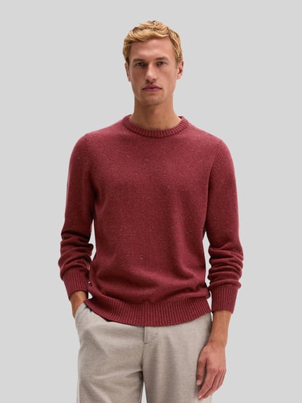 Männermodel trägt Pullover mit Logo-Detail von MARC O'POLO in melierter Strickoptik mit Struktur und Rippbündchen, Ganzkörperansicht von vorne.
