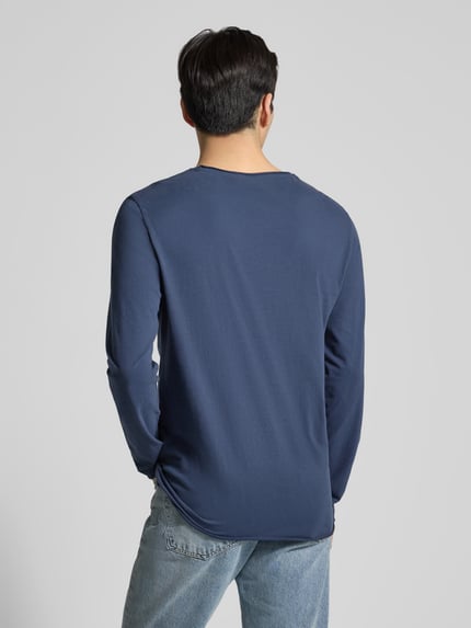 Männermodel trägt Regular Fit Langarmshirt aus reiner Baumwolle Modell 'JAAMES' von Armedangels in Dunkelblau, Ganzkörperansicht Rückansicht. Unifarbene Optik, Rollsaum an Ärmeln und Rumpf, Jersey-Textur.