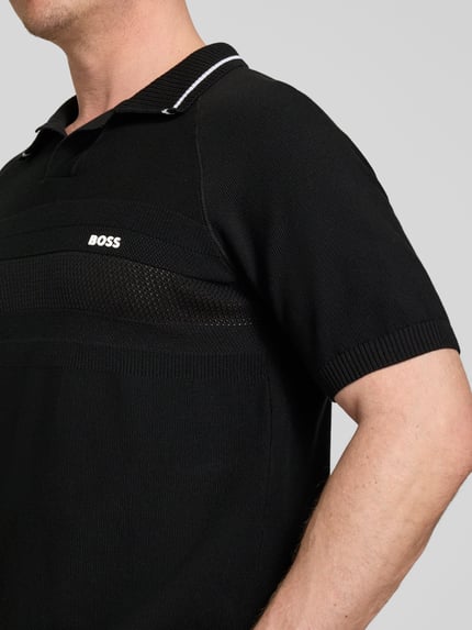 Männermodel trägt Regular Fit Poloshirt aus Strick von BOSS Green in Schwarz, Strickoptik, Polokragen, Kurzarm, reine Baumwolle, Nahaufnahme Oberkörper.