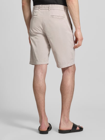 Männermodel trägt Tapered Chinoshorts aus Baumwoll-Mix von BOSS Orange, Optik: Unifarben, Materialverarbeitung: Twill, Ganzkörperansicht Rückansicht.
