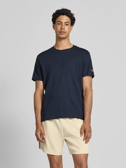 Männermodel trägt T-shirt mit Labelstitchings und ronde hals van CHAMPION, puur katoen, regular fit, ruglengte bij maat M 66 cm, ganzlichaamsvooraanzicht.