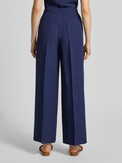 Vrouwenmodel draagt Stoffhose aus Viskose-Leinen-Mix Modell 'PERA' van EMME, donkerblauw, wijde pijp, steekzakken, persplooien, totaalbeeld achteraan.