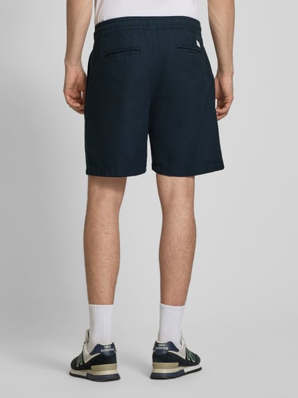 Męski model nosi Relaxed Fit Chinoshorts aus Baumwoll-Leinen-Mix od Pepe Jeans, granatowy kolor, jednolity, luźny krój, elastyczny pas z troczkiem, kieszenie boczne i pasplowane, bawełniano-lniana faktura, widok całej sylwetki od tyłu.