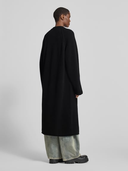 Frauenmodel trägt Funktionsjacke mit einreihiger Knopfleiste von black palms in Melange-Optik, Struktur, Longline, langarm, Rückansicht.